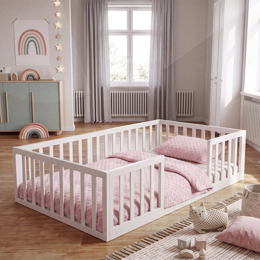 Weiß lackiertes Montessori-Bodenbett im Kinderzimmer mit Regenbogen-Poster, Sternenlichtern und rosa Bettwäsche. Vollständig KI-generiert.