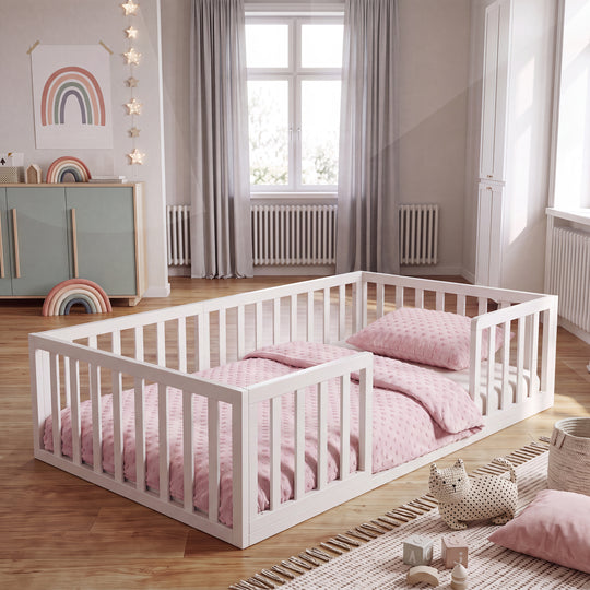 Weiß lackiertes Montessori-Bodenbett im Kinderzimmer mit Regenbogen-Poster, Sternenlichtern und rosa Bettwäsche. Vollständig KI-generiert.