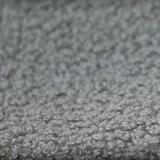 Gros plan du revêtement en tissu bouclé gris et texturé du lit enfant.
