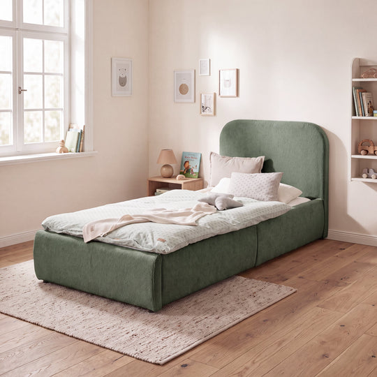 Lit enfant vert en bouclé dans une chambre d'enfant lumineuse avec mur de cadres et bibliothèque. Entièrement générée par IA.