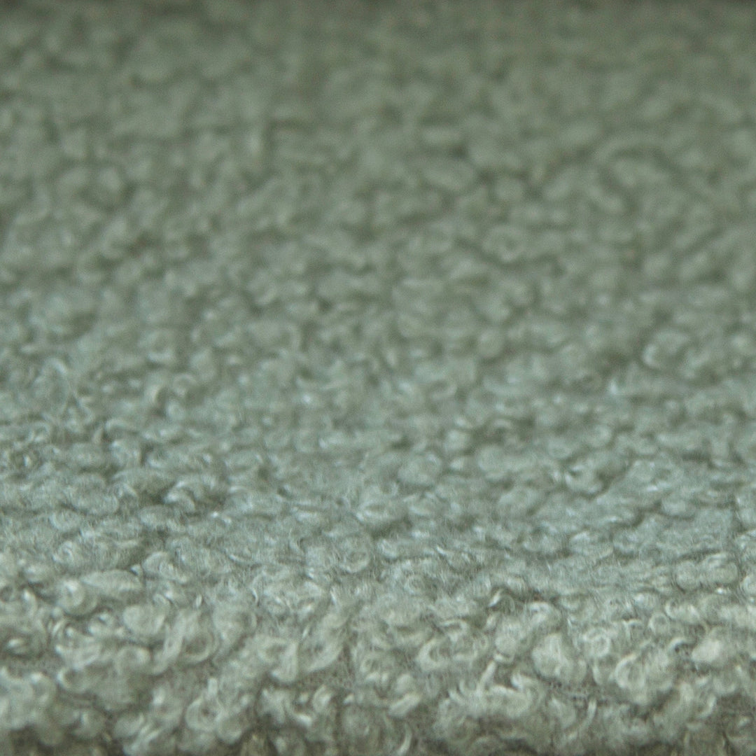 Gros plan du revêtement en tissu bouclé vert et texturé du lit enfant.