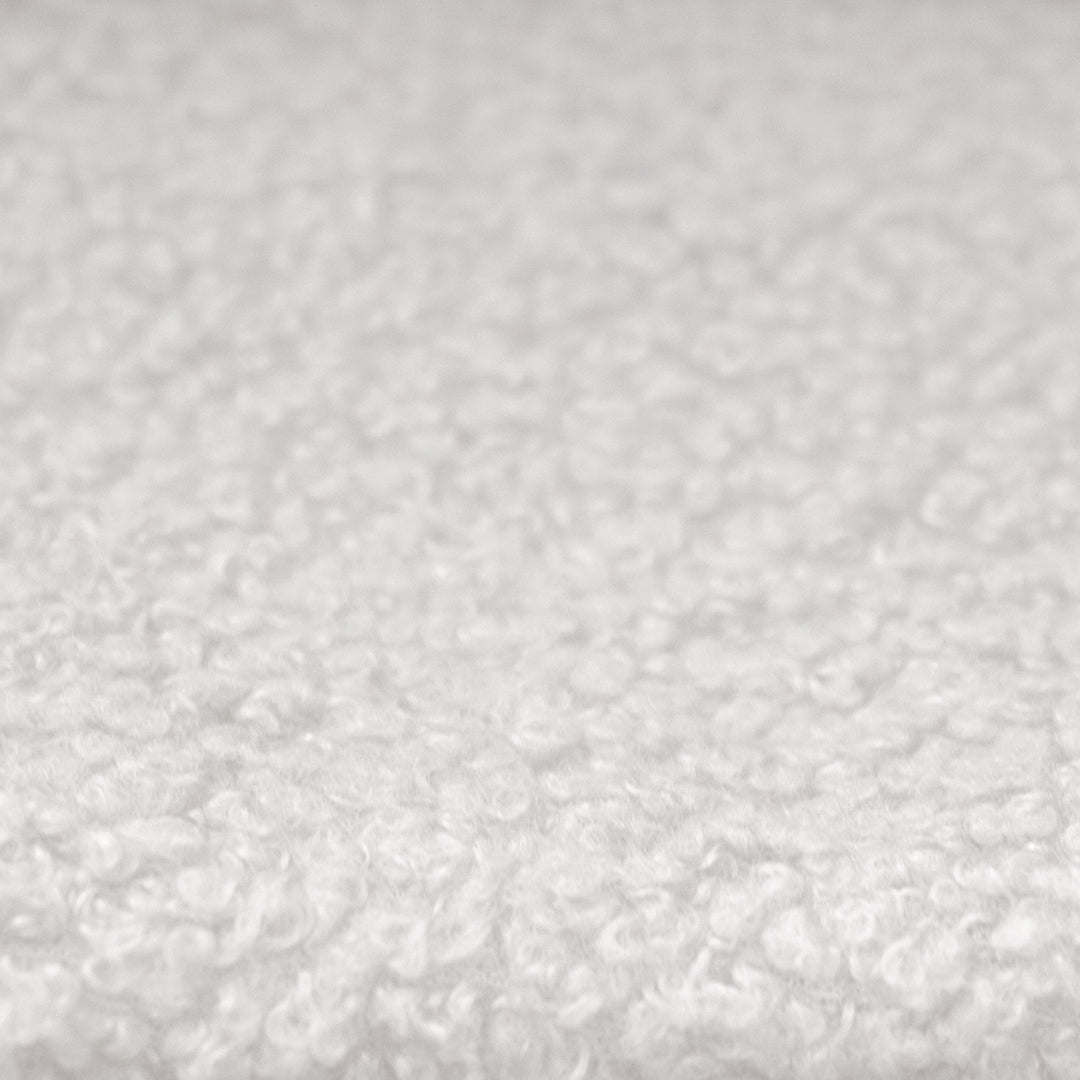 Gros plan du revêtement en tissu bouclé blanc et texturé du lit enfant.