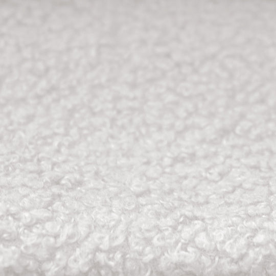 Gros plan du revêtement en tissu bouclé blanc et texturé du lit enfant.