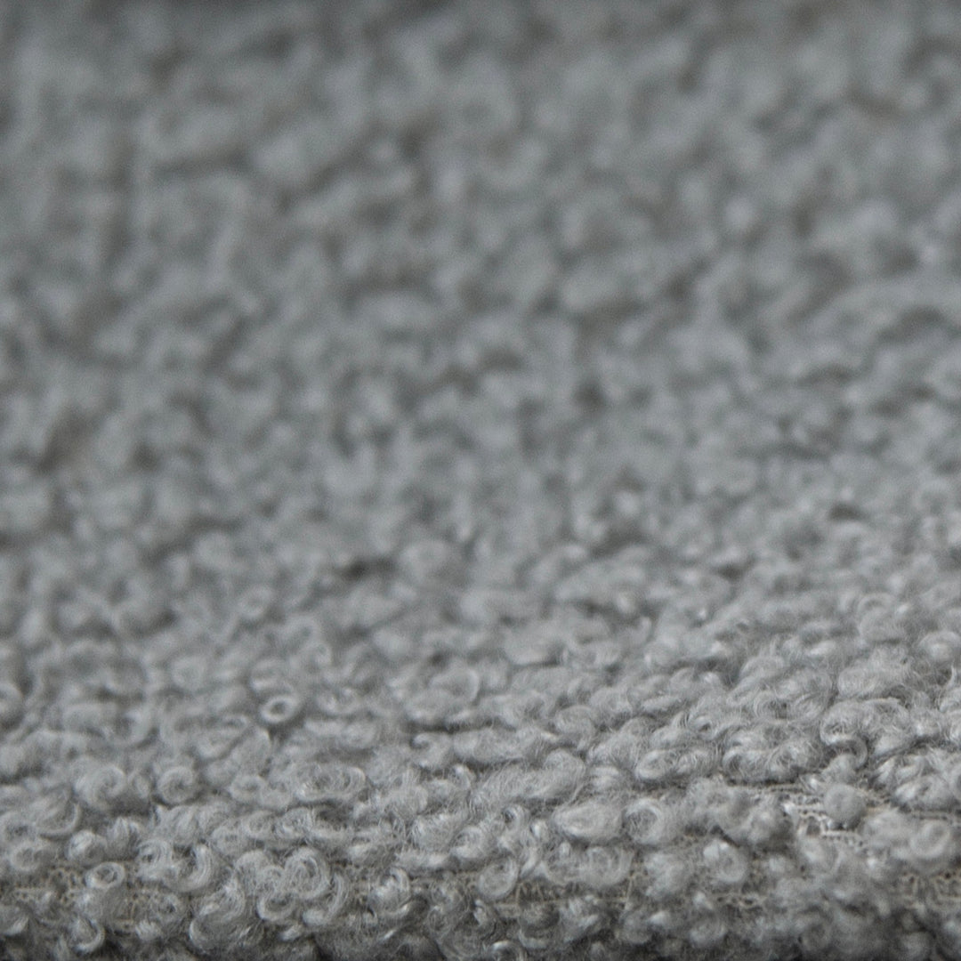 Gros plan du revêtement en tissu bouclé gris et texturé du lit.