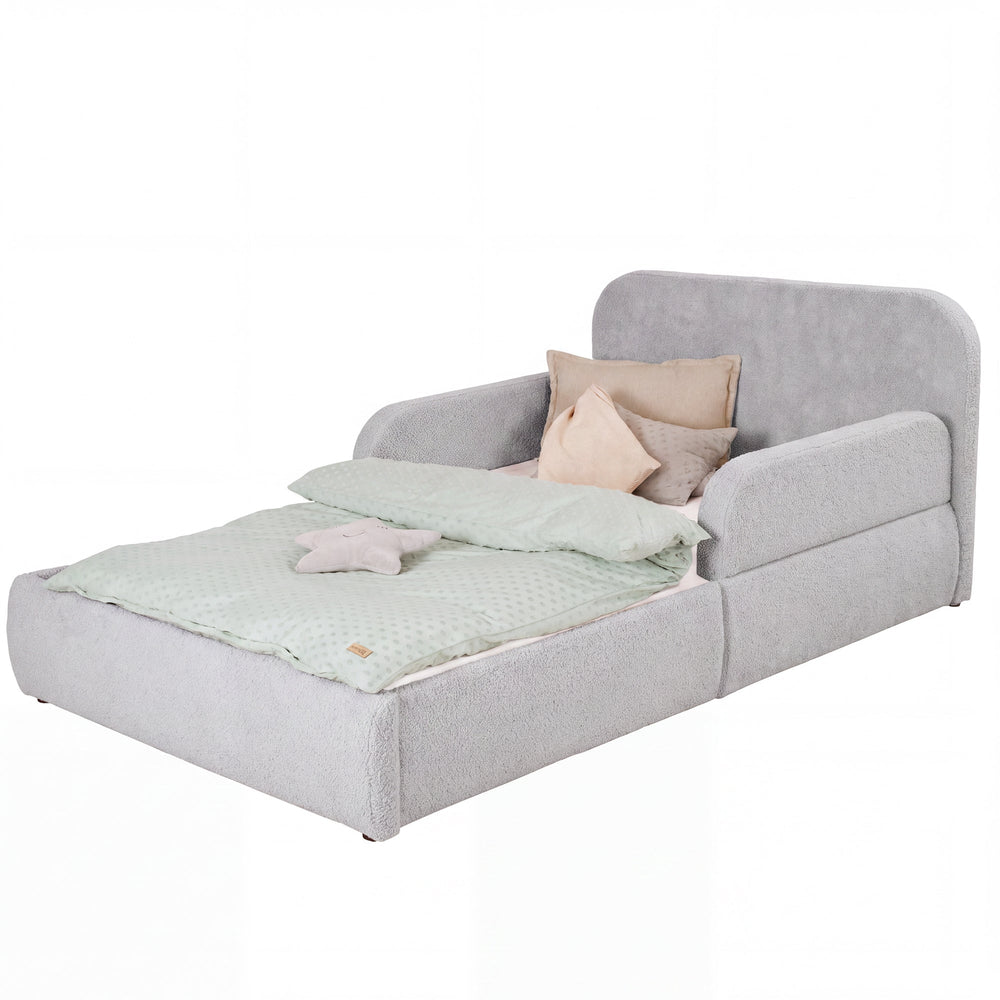 Lit enfant roba Little Dream gris clair avec tête de lit et protections latérales, garni de linge de lit et de coussins. Partiellement générée par IA.