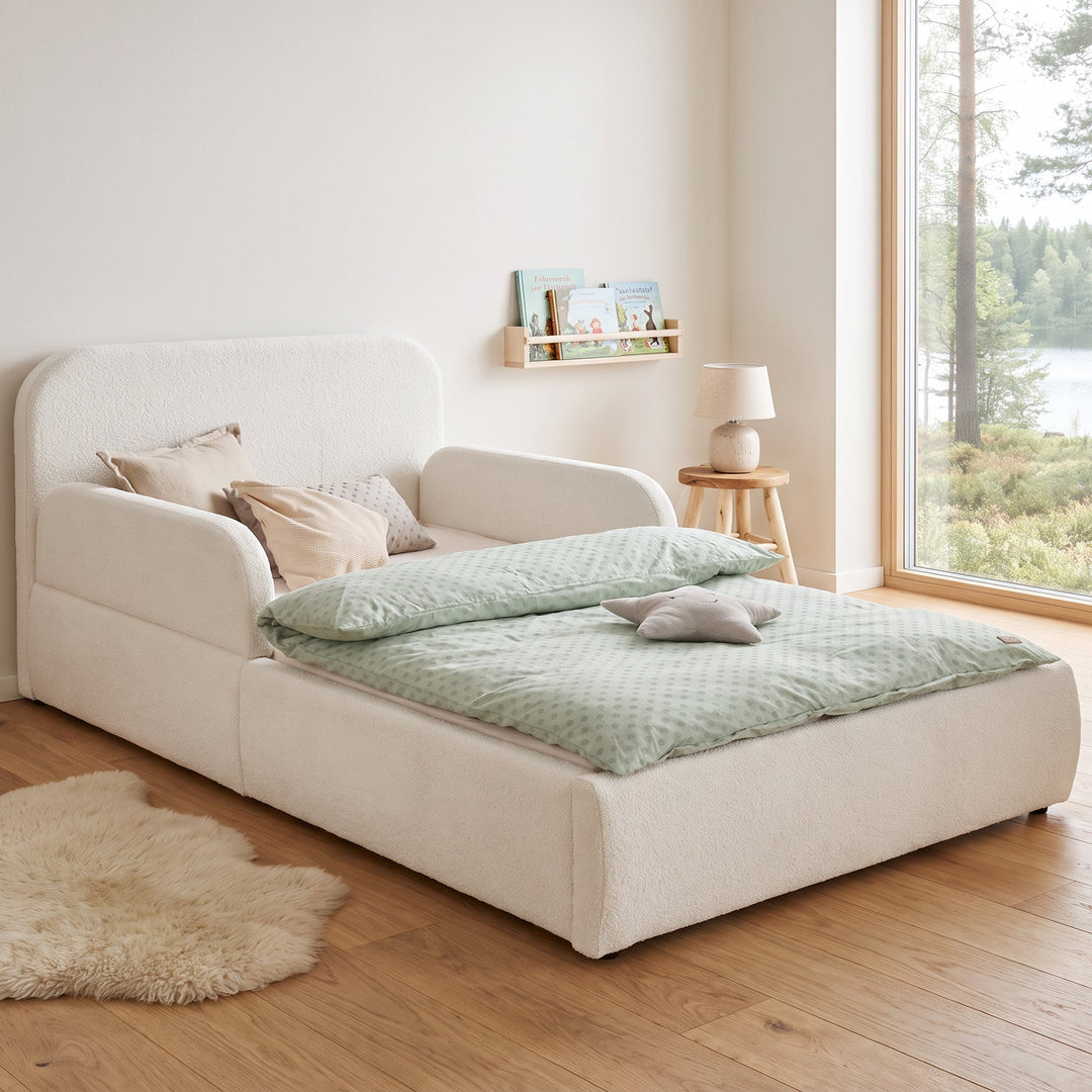 Lit enfant roba Little Dream blanc dans une chambre d'enfant avec vue sur le lac, bibliothèque et tapis en peau de mouton. Partiellement générée par IA.