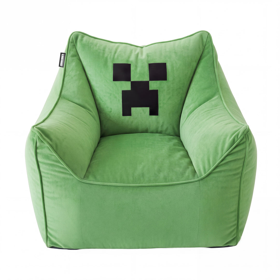 Sillón puf verde con reposabrazos y cara pixelada negra de Creeper en el respaldo, vista frontal sobre fondo blanco. Generada íntegramente con IA.
