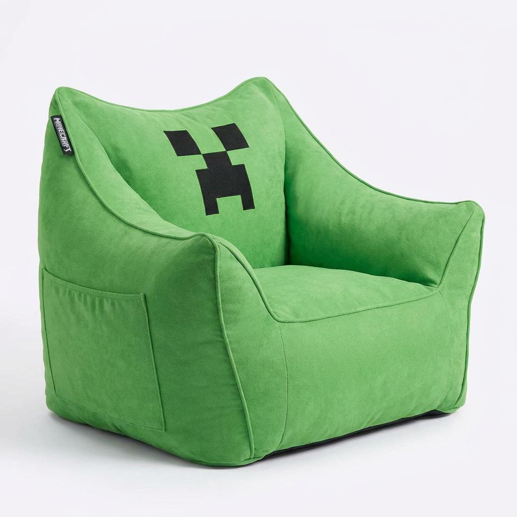 Sillón puf verde con cara de Creeper en vista oblicua, bolsillo lateral visible, sobre fondo blanco.