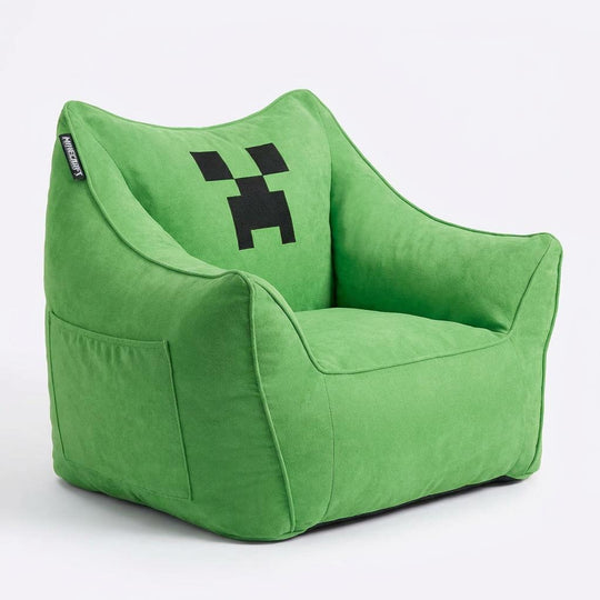 Sillón puf verde con cara de Creeper en vista oblicua, bolsillo lateral visible, sobre fondo blanco.